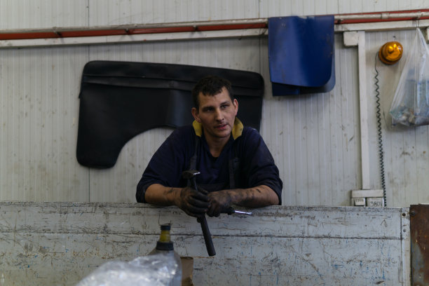 汽车修理工拿着锤子在修理厂。图片下载