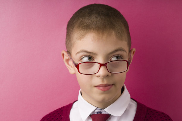特写肖像的孩子与眼镜避免眼神接触看一边得到了不愉快的尴尬情况感到尴尬。红色的背景图片下载