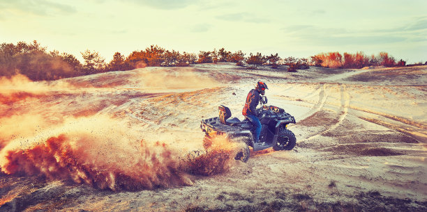 青少年在沙丘上驾驶ATV在沙地上转弯图片下载