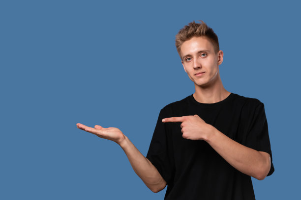 帅气的年轻人在黑色t恤指着空白的广告在他的手掌图片下载