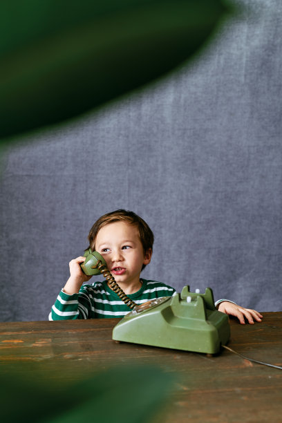 可爱的孩子使用手机复古风格。2-3岁的孩子用复古风格的手机说话。图片下载