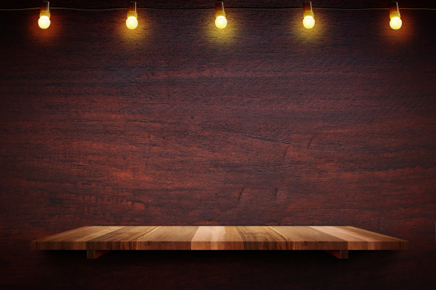 空的棕色木板木架在黑色红色的木墙背景与灯泡串，模型展示或蒙太奇的产品或设计。图片下载