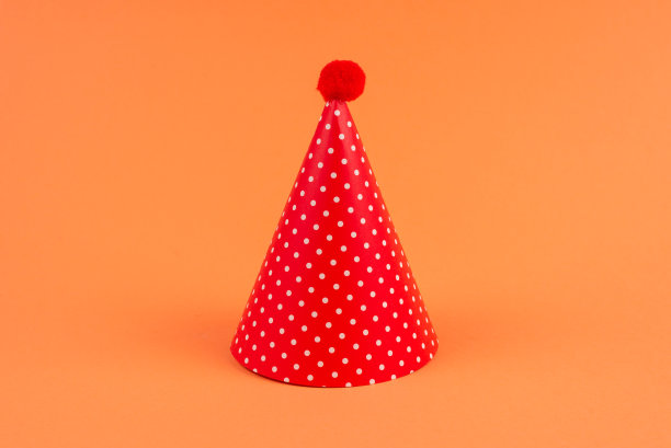 橙色背景的彩色生日帽。图片下载