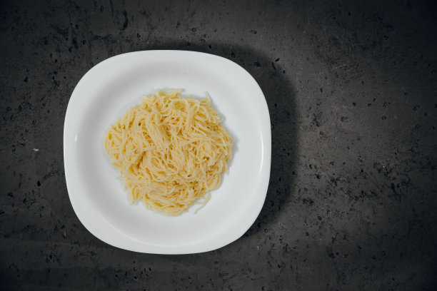 顶视图上的白色盘子和意大利面在一个深色的石材台面上。图片下载