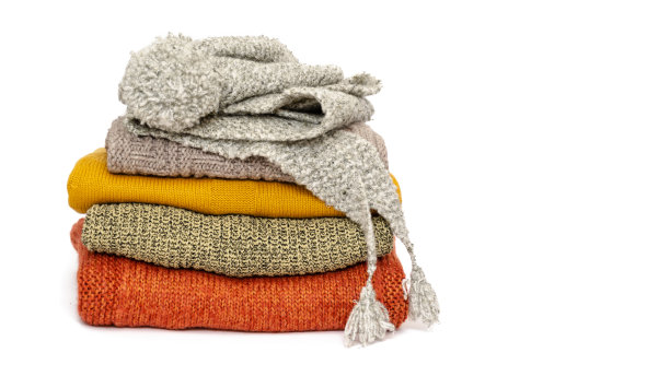 一叠叠叠的暖和的女式针织毛衣，围巾和帽子在白色的背景上。保暖的季节。本空间图片下载