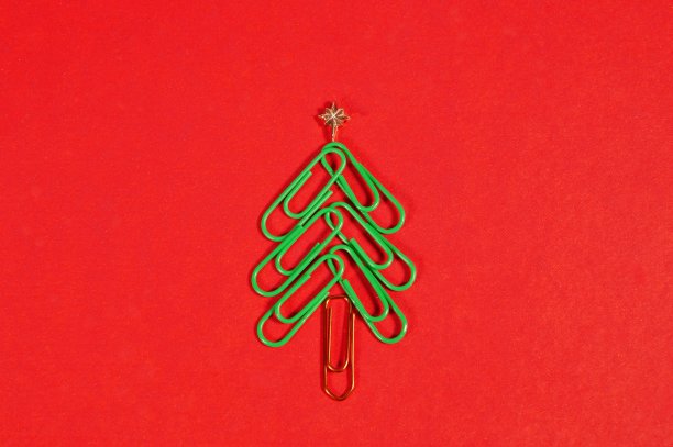 概念:办公室圣诞快乐。红色背景上的回形针制成的圣诞树。回形针圣诞树。圣诞节的背景。图片下载