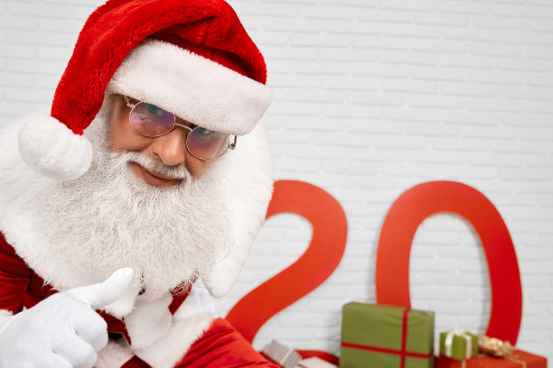 圣诞老人的特写靠近白色的墙与拇指向上图片下载