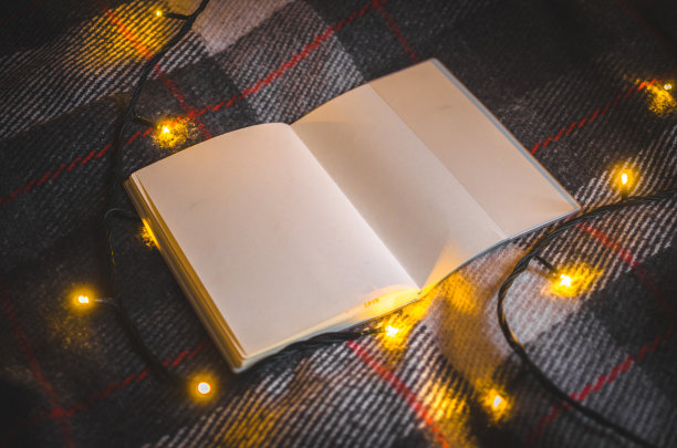 空白笔记本上一个舒适的格子与圣诞灯在冬青冬夜概念照片图片下载