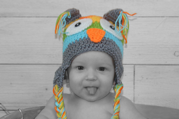 黑白两色流行照片的婴儿男孩在猫头鹰针织帽和舌头图片下载