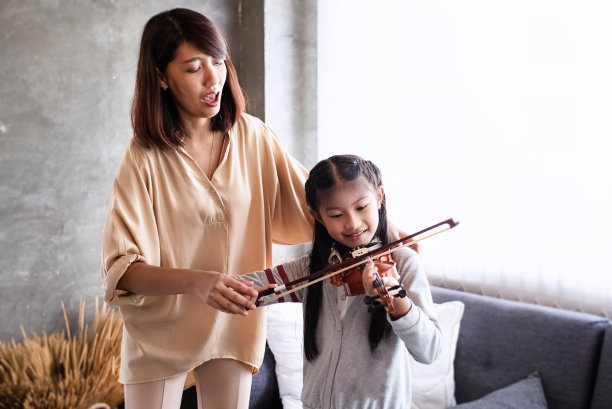 老师教小女孩拉小提琴，上音乐课，在画室里，心情舒畅，灯光朦胧图片下载