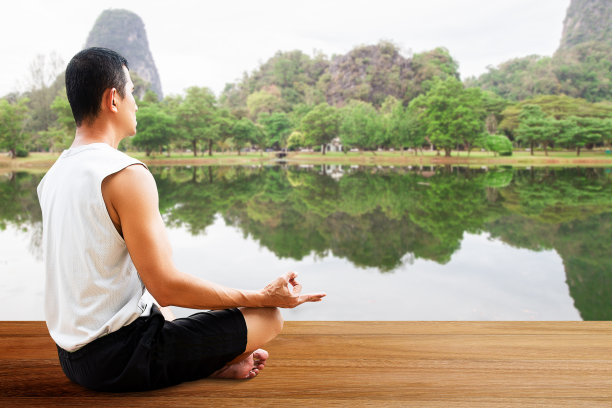 一个男人在模糊的湖背景下的木地板上沉思图片下载