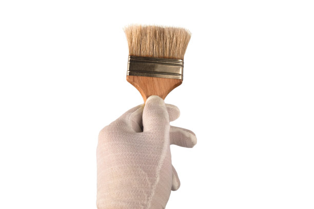 戴着白手套的手拿着一把刷子。孤立的特写白色背景。绘画装饰、家装或装修的概念。画笔作为染色的工作工具图片下载