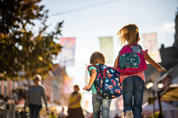 后视图小男孩和小女孩手牵着手跑在街上图片下载