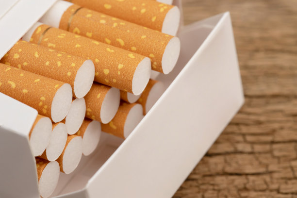 把它从烟盒上剥下来，准备吸烟。包装整齐摆放在木桌上。照片滤镜自然光。图片下载