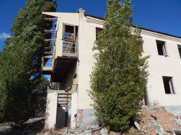 一栋被毁的两层楼房子的废墟，还有一个阳台。砖破建筑的照片。图片下载