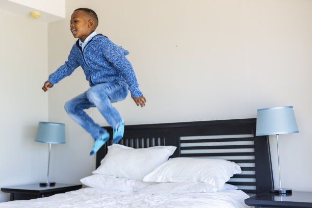 兴奋的小男孩在床上跳图片下载