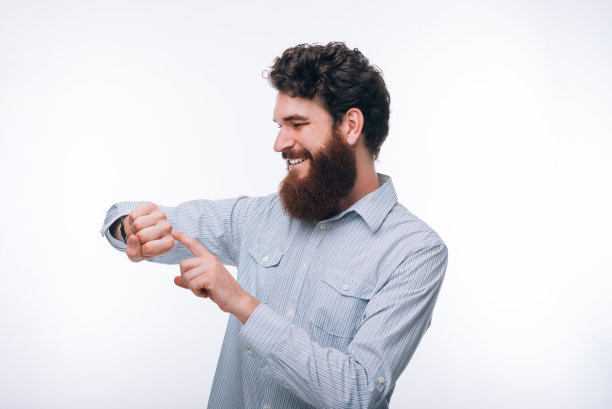 一张愉快的留着胡子的男人随意使用他的智能手表的照片图片下载
