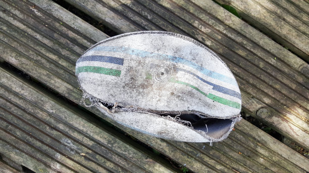 白色皮革撕裂的橄榄球在木板的背景图片下载