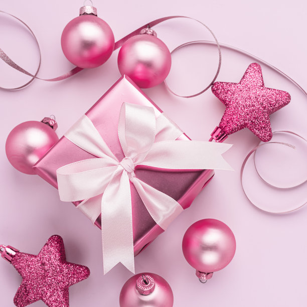 有缎子蝴蝶结和粉色玩具球在粉背景的节日盒。平的风格。节日的概念。副本的空间。图片下载