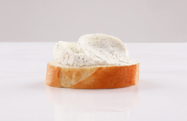 将芝士和香草涂在切片的法式长棍面包上，西班牙小吃放在白色背景上图片下载