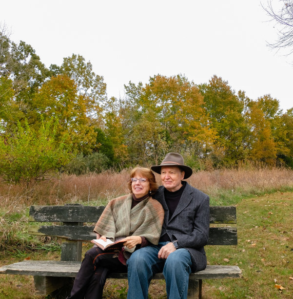 微笑的老年夫妇坐在长椅上的秋天图片下载