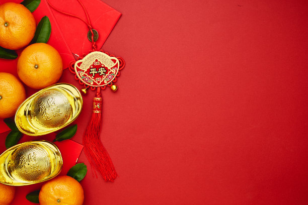 中国幸运币或中国结和中国金锭以及传统中国结（外文意思是祝福）和红包以及在红色背景上用新鲜橙子装饰素材图片
