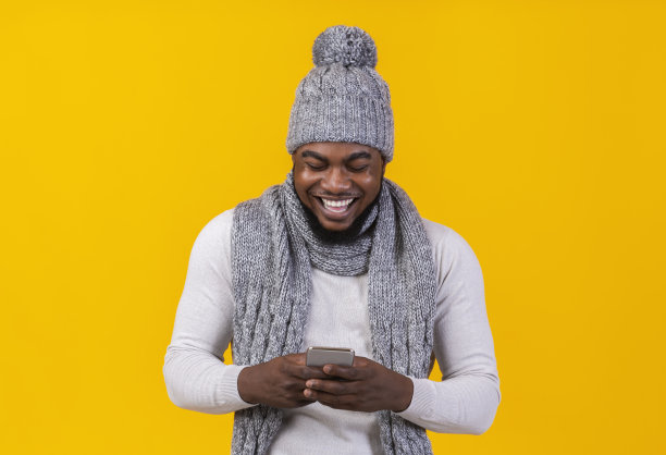 微笑的非洲裔美国人用黄色背景的智能手机图片下载