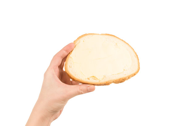 面包和黄油在女人的手孤立在白色的背景。图片下载