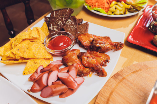 健康膳食在节日餐桌上为聚会服务。朋友们在木制桌子上用有机食物庆祝。男人和女人互相传递盘子。图片下载