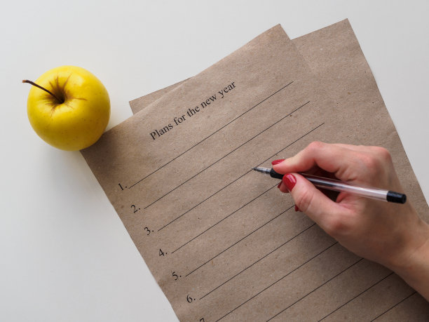 新年的计划。牛皮纸上的文字。在一个女人手里的圆珠笔图片下载