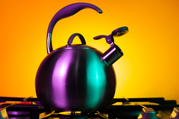 黄色背景下霓虹灯下的不锈钢水壶的照片。图片下载