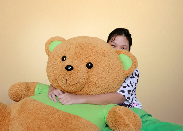 小女孩的肖像坐在房间里拥抱泰迪熊。快乐的女孩和小熊。——图片图片下载