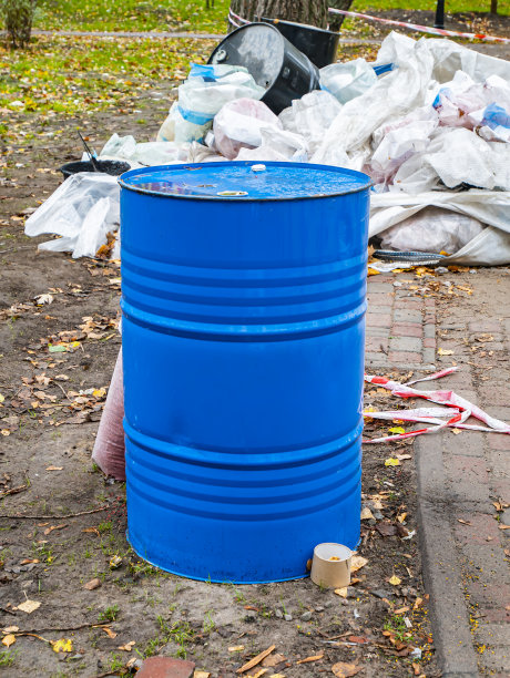 蓝色金属桶背景是建筑残骸。图片下载