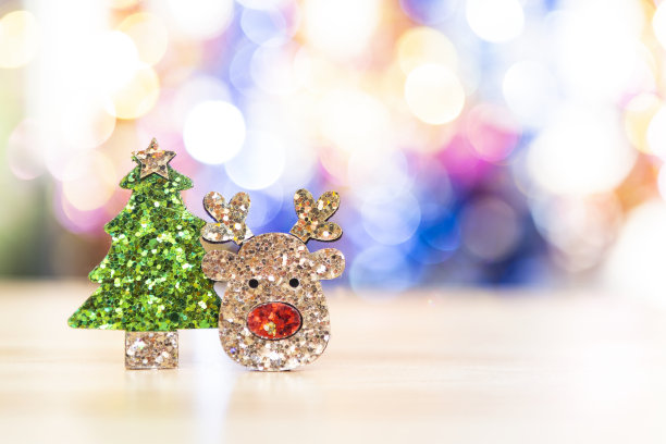驯鹿的脸与闪闪发光的绿色圣诞树在模糊的彩色散焦背景图片下载