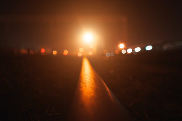 火车轨道在夜晚远处的橘黄色灯光下图片下载