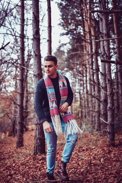 英俊的男性与装饰披肩走过秋天的森林图片下载