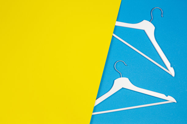 两个白色木制衣架，黄色和浅蓝色背景。购物，促销，社交媒体，新季概念图片下载