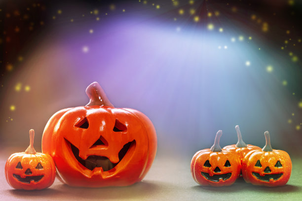 小微笑的橙子和大微笑的南瓜在明亮的，黑色的，多彩的背景上。图片下载