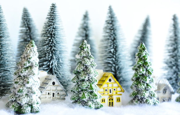 森林里有房子的迷你雪圣诞树。散景灯的背景。图片下载