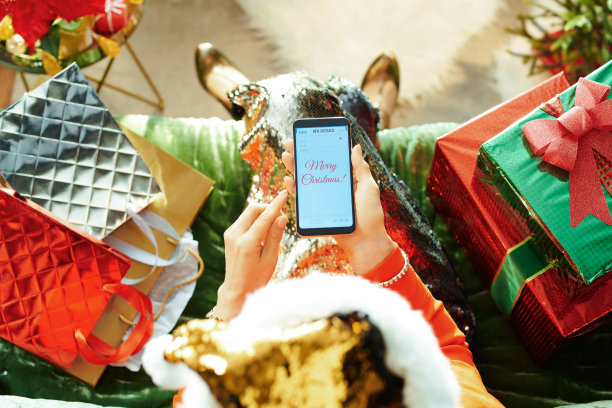 时尚女性在智能手机上写圣诞祝福邮件图片下载
