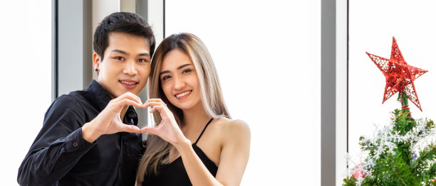 浪漫的小情侣在派对上一起庆祝圣诞和新年，心形的手势。图片下载