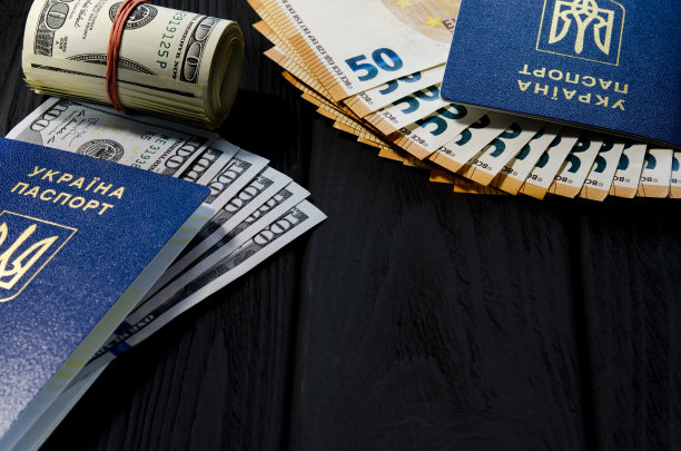 一卷用红色橡皮筋捆着的厚厚的旧百元钞票，旁边是一名乌克兰公民的生物识别护照，里面是50欧元钞票图片下载