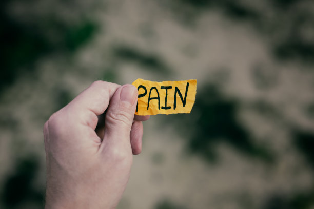 一个男人手里拿着一张黄色的纸，上面写着“疼痛”图片下载