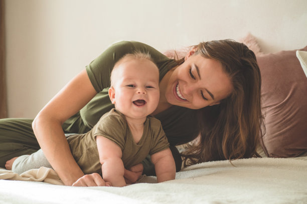 一个小男孩和妈妈在床上的家庭照片。妈妈抱着并亲吻她的孩子。图片下载