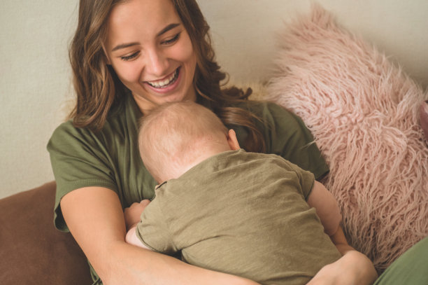 一个小男孩和妈妈在床上的家庭照片。妈妈抱着并亲吻她的孩子。图片下载