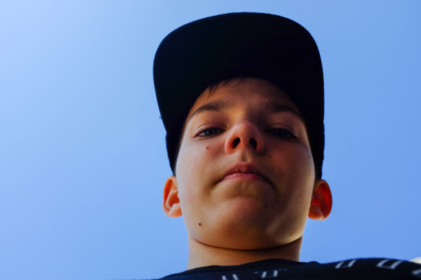 头戴一顶帽子，低头看镜头的少年图片下载