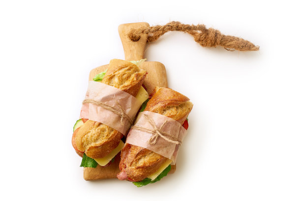 两个新鲜的长棍三明治与培根，切德奶酪，芥末，生菜和蔬菜在切板孤立的白色背景图片下载