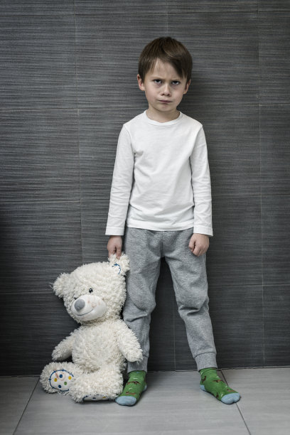 学龄前的愤怒男孩抓着泰迪熊的耳朵图片下载