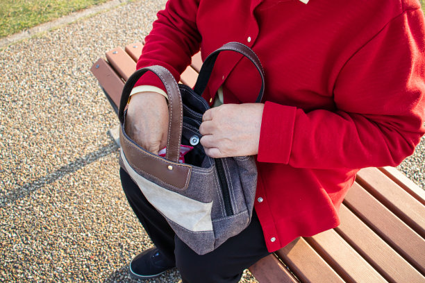 一位上了年纪的妇女在检查一个包里的东西。图片下载