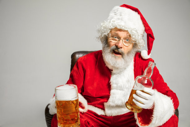 圣诞老人坐在扶手椅上喝啤酒，祝贺2020年新年图片下载